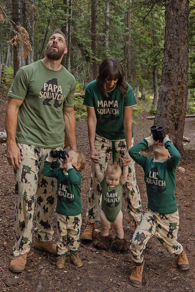 a family under trees in a forest wearing Sasquatch themed family pajamas 