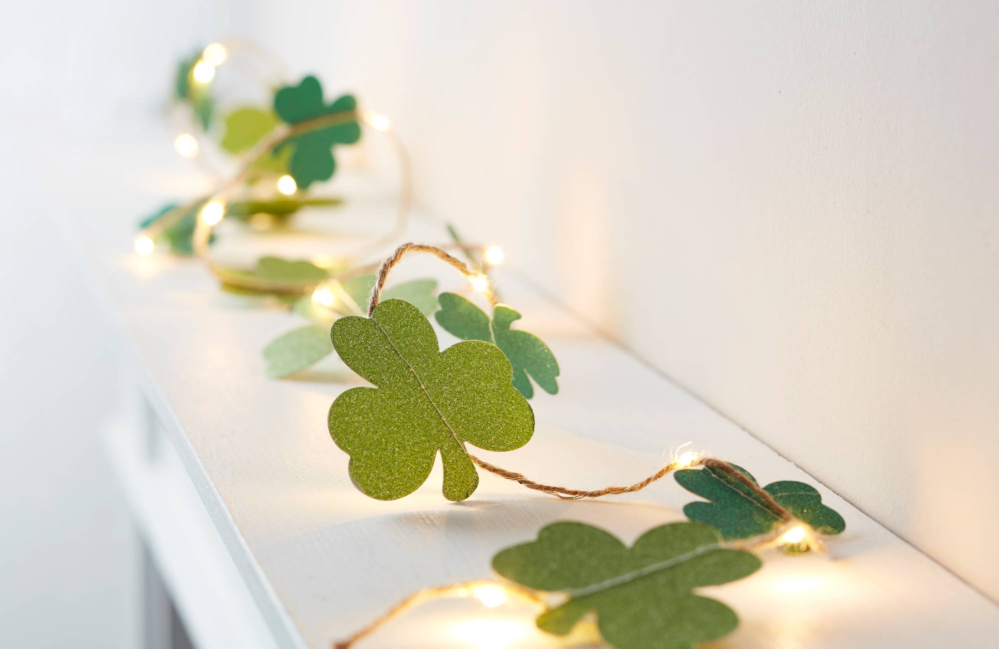 Shamrock fairy light green garland decoration on a white mantlepiece.