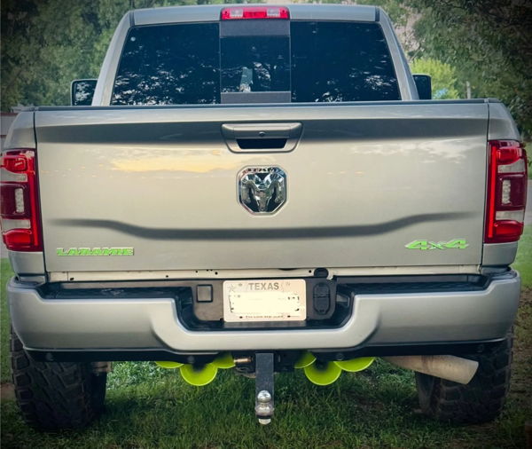 Rear view of silver RAM Laramie 4x4 with lime green badges and five green train horns mounted under bumper