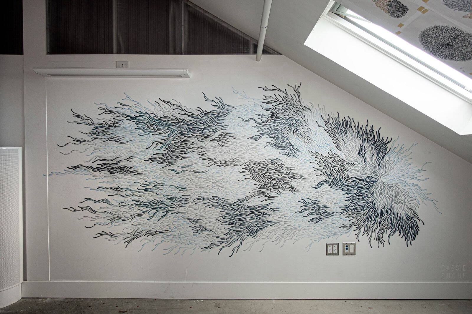 A large, abstract, blue and grey mural painted on a white wall. 