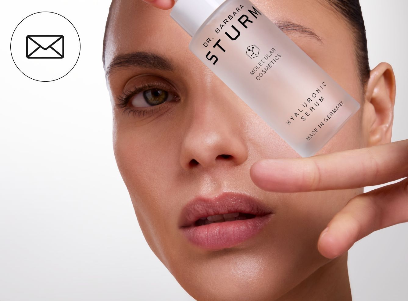 A woman holding a skincare product near her face.
