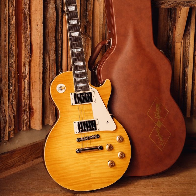 A yellow electric guitar next to a brown guitar case.