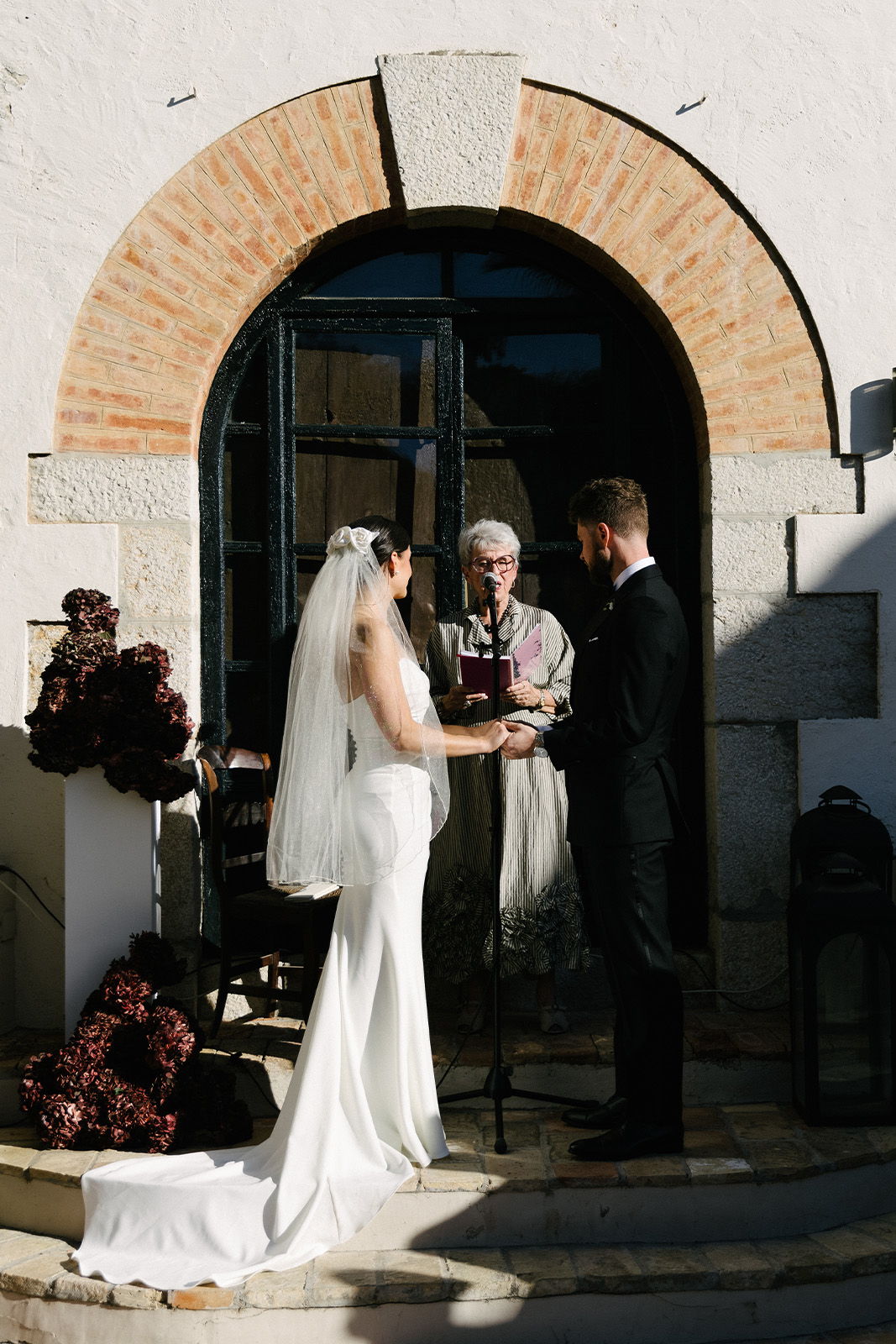 Bride and groom exchanging vows during a wedding ceremony outdoors.