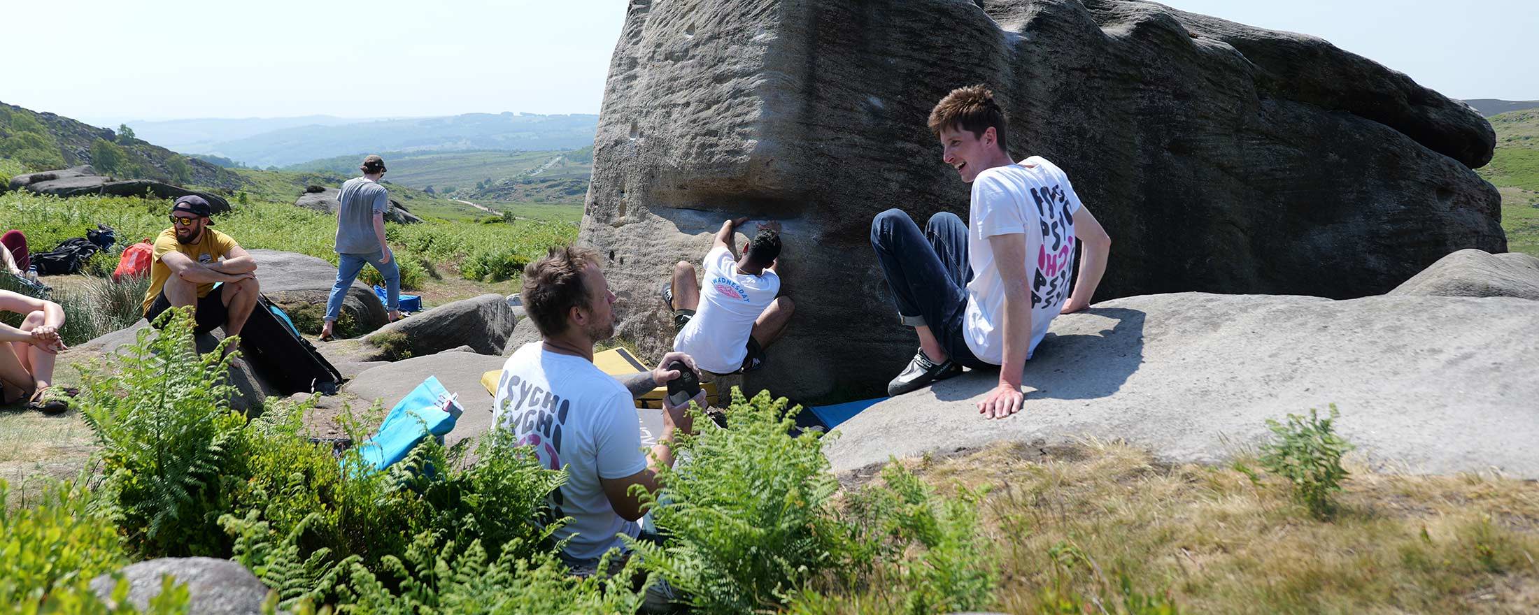 Psychi rock climbing team of athletes climbing on boulder at Stanage Plantation in the Peak District 