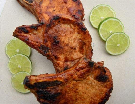 Grilled meat with lime slices on a white plate.