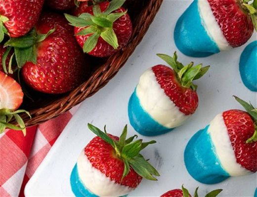 Bowl of strawberries with blue and white chocolate-dipped strawberries on a plate.