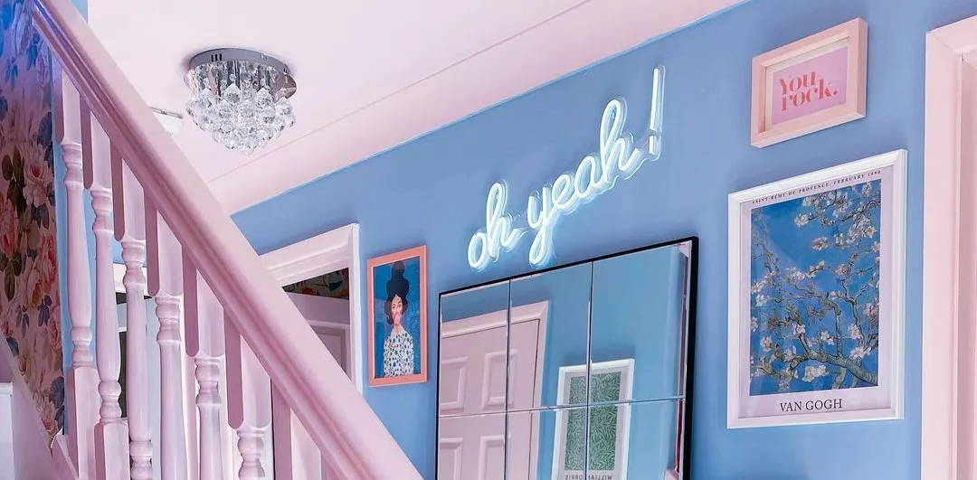 A bright blue hallway with pink accents and a neon 'oh yeah' sign.