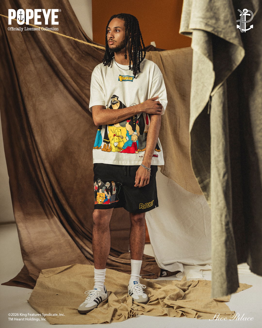 A person wearing a graphic t-shirt and shorts, posing in a studio setting.