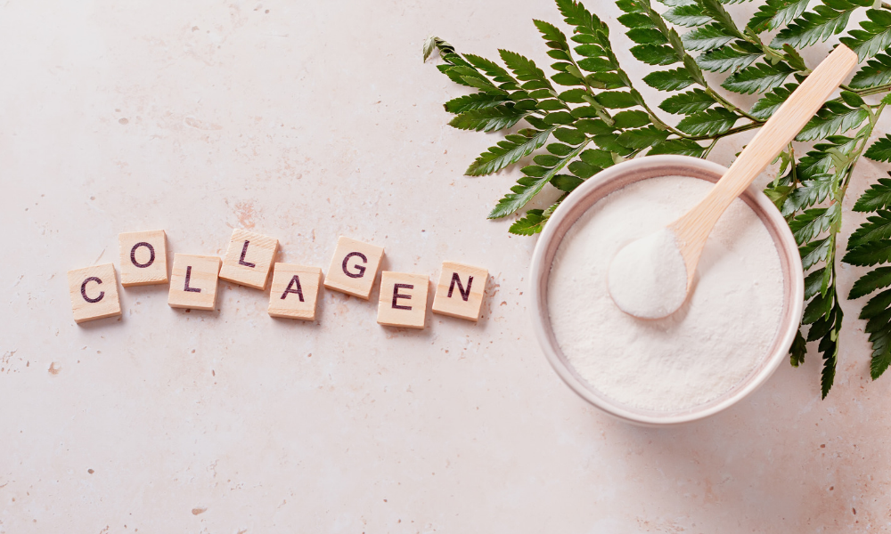Collagen powder in a bowl with wooden scoop and decorative leaves.