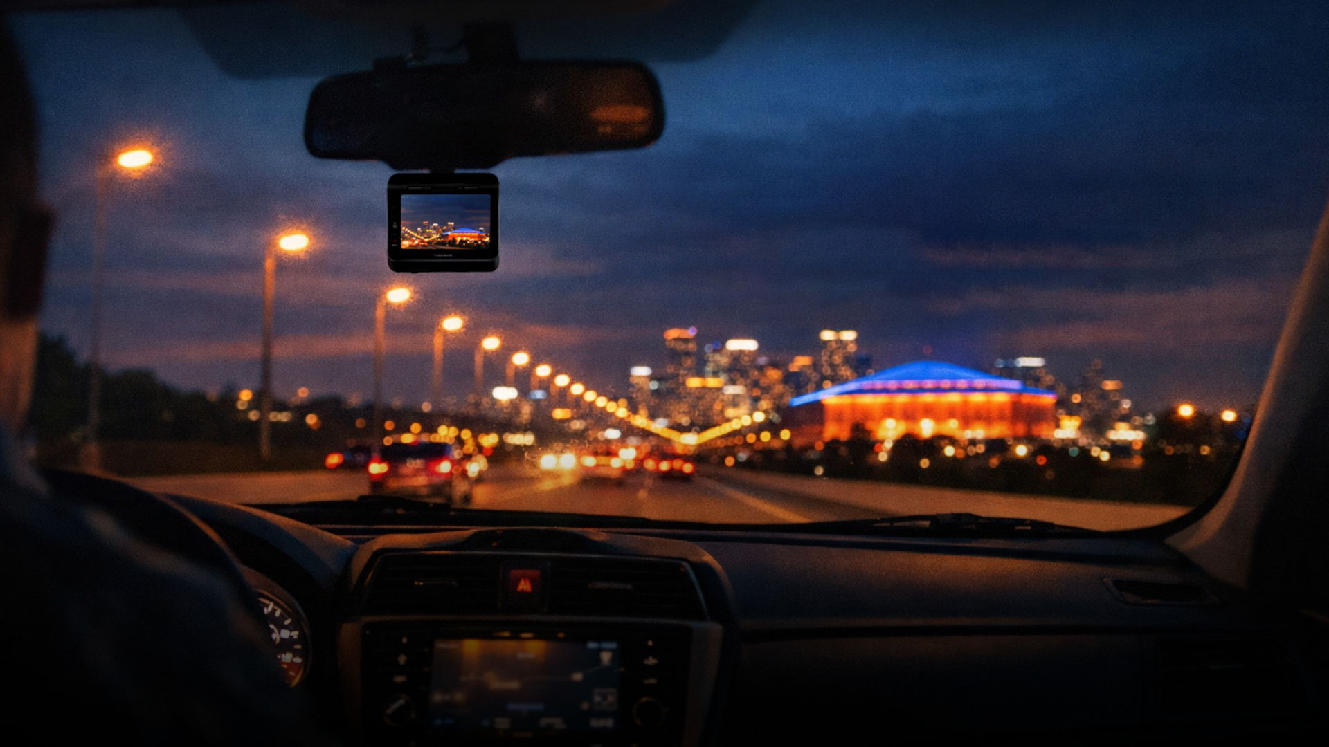 View from a car driving at night, city lights ahead.