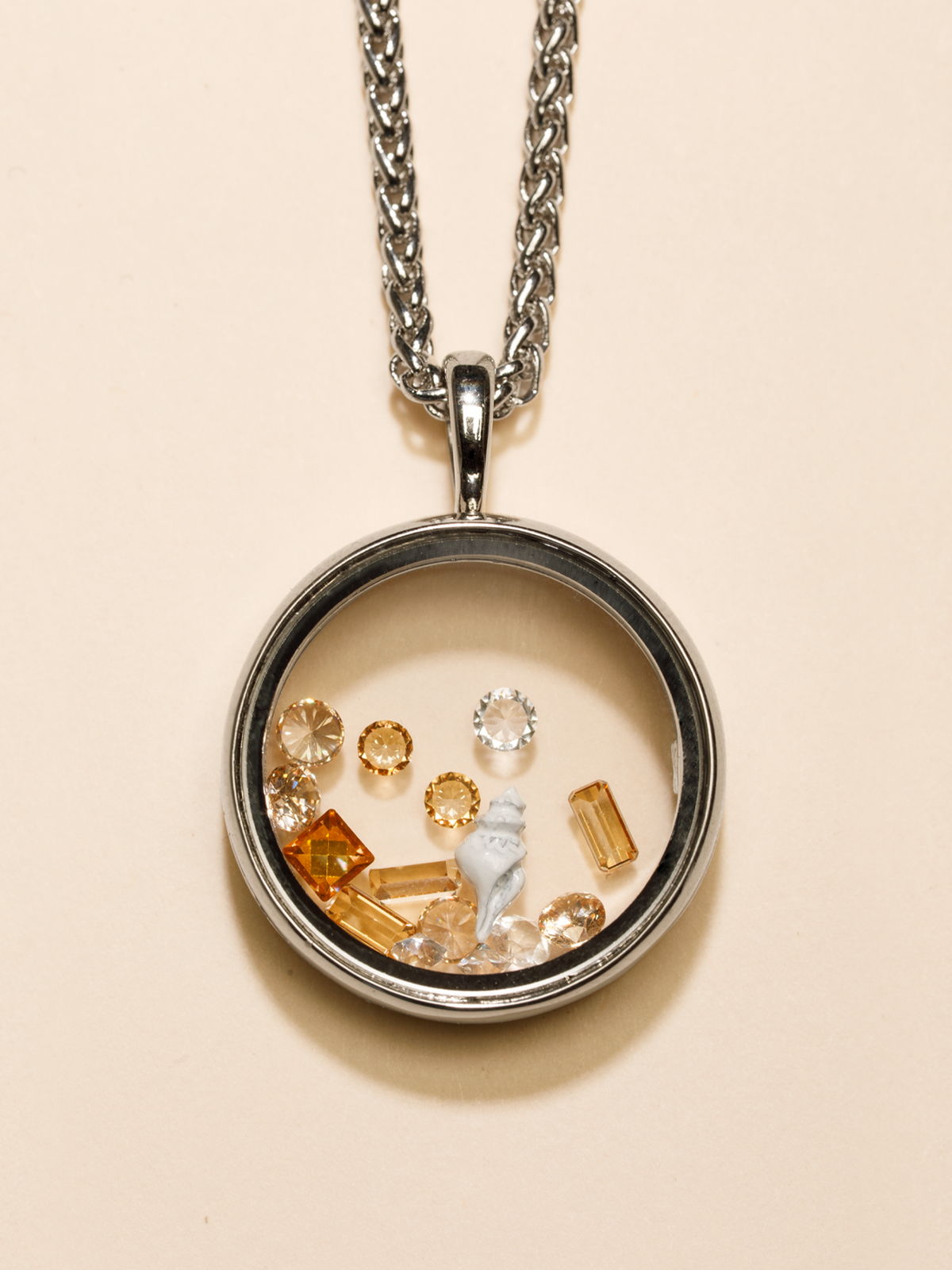 Silver Living Locket necklace filled with crystals and charms displayed on a neutral background.