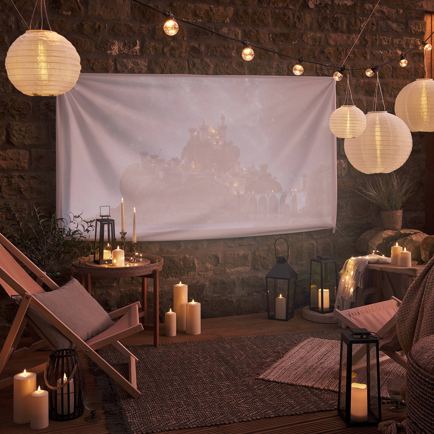 An outdoor movie night setting with LED candles, lanterns, solar hanging lanterns and warm white festoon lights.