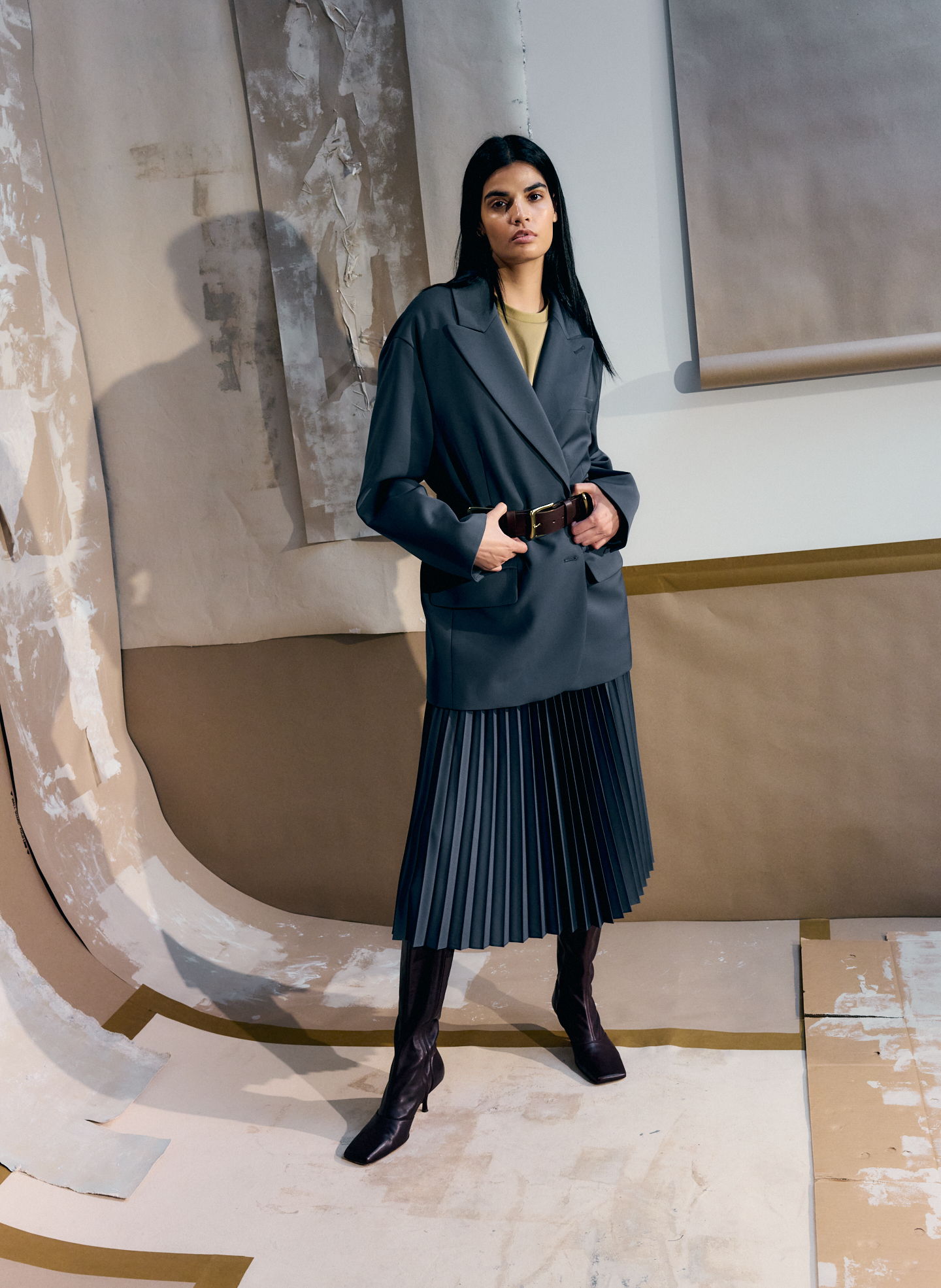 A model wearing a stylish outfit stands against a textured background.