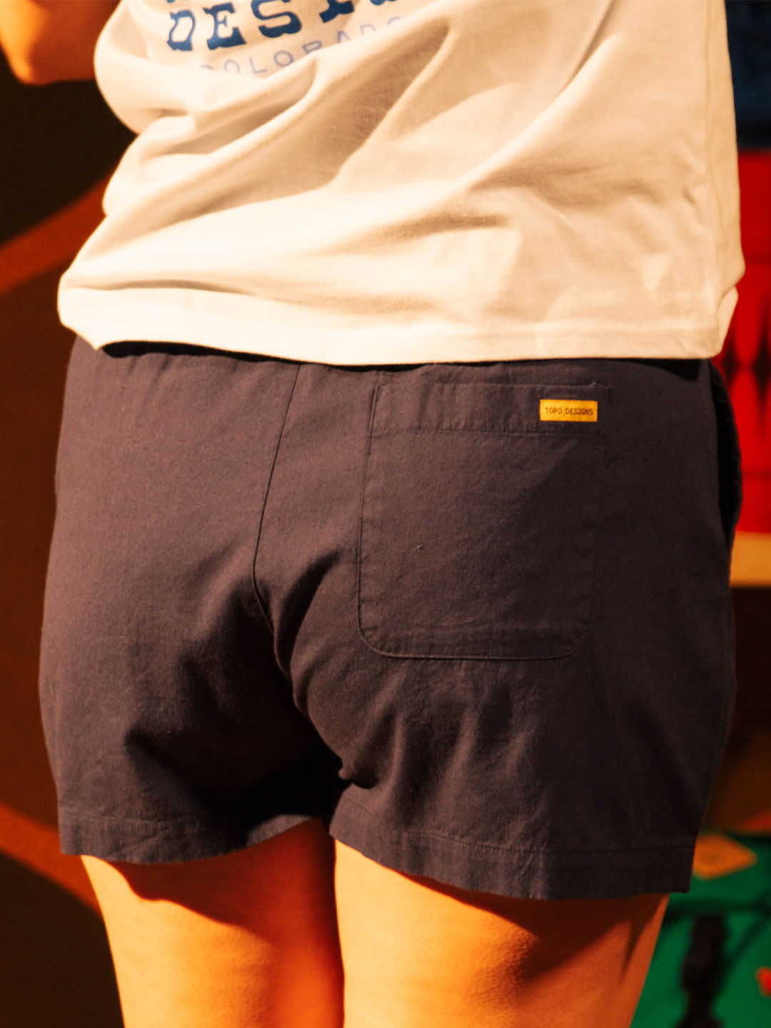 Person wearing a white shirt and navy shorts, viewed from behind.