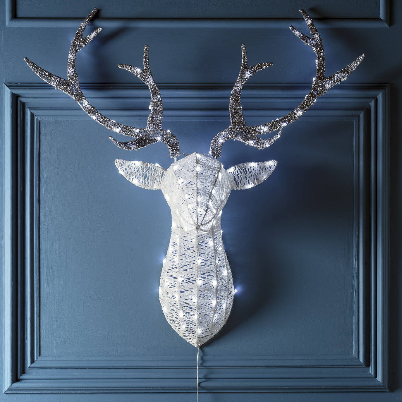 Glitter stag head silhouette Christmas light entwined with white LED hanging in a dining room