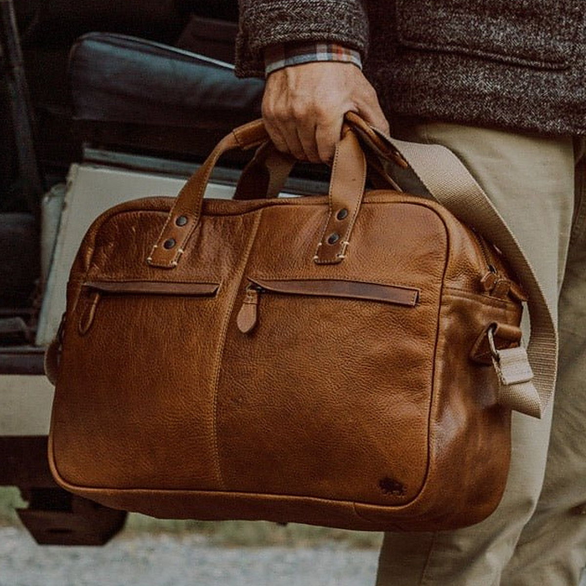 Hand carrying a Buffalo Jackson tan full-grain leather briefcase with a shoulder strap