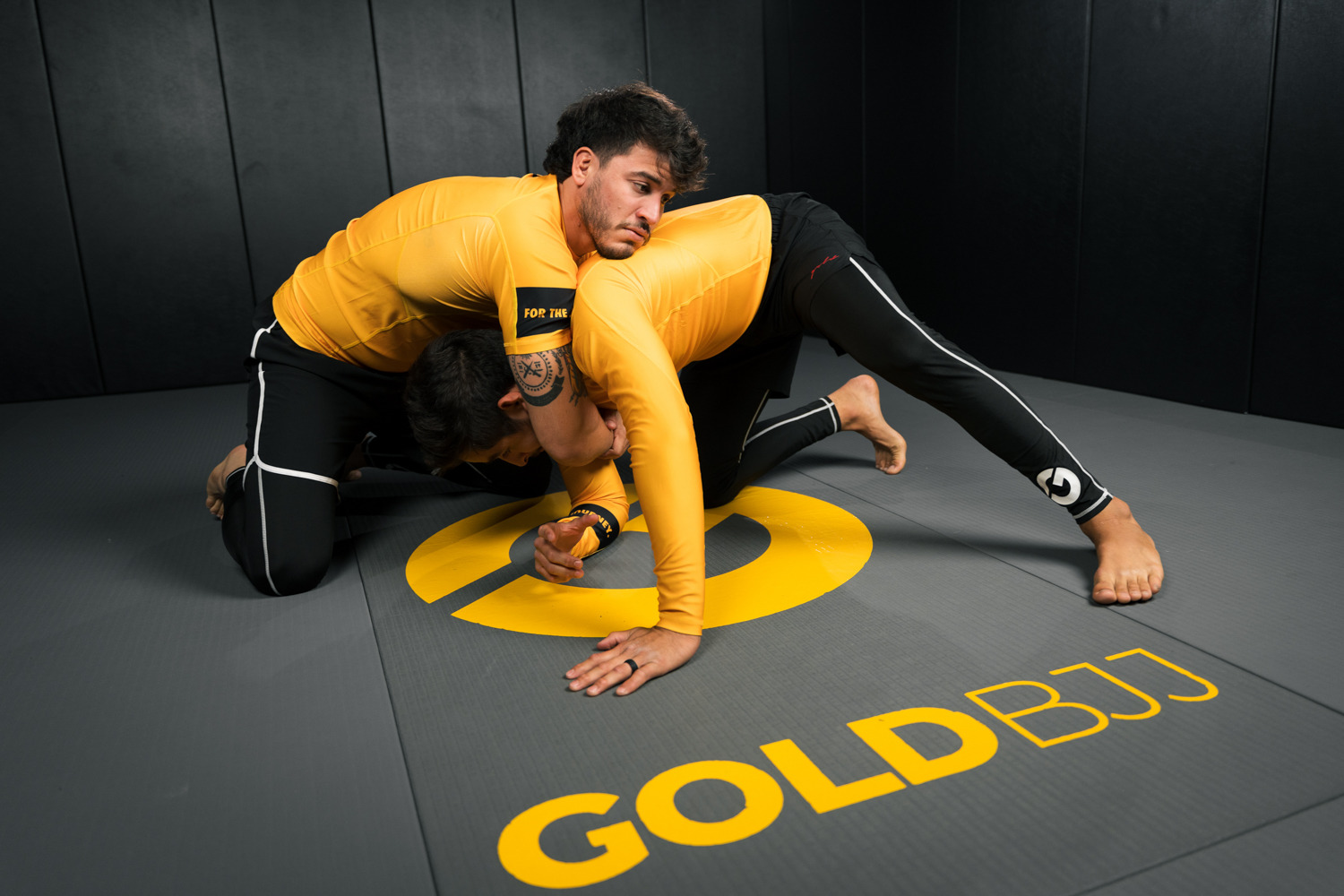 Two athletes grappling on a mat with 