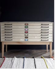 Wooden dresser with colorful handles on a patterned rug.