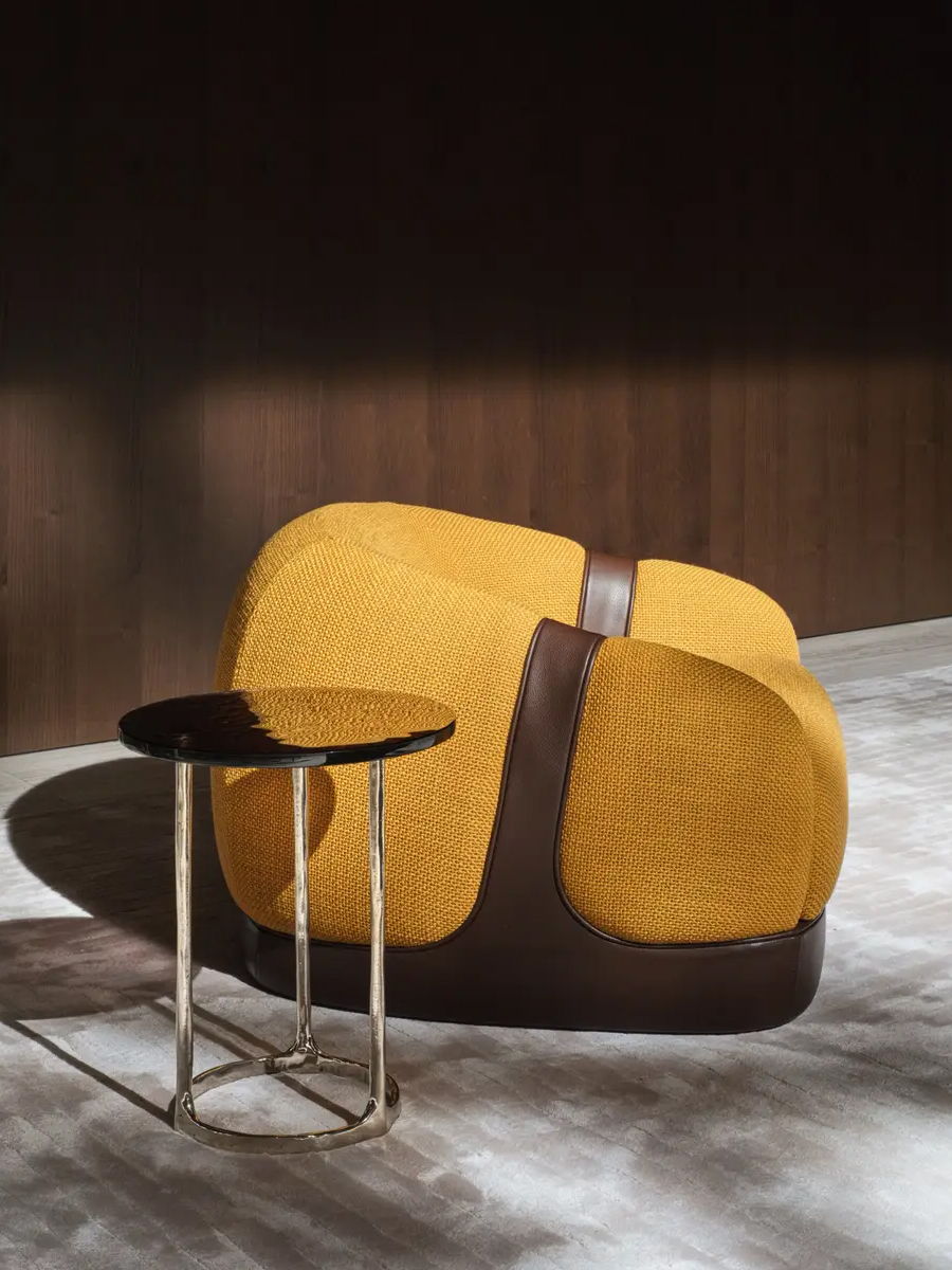 A stylish Corsetto yellow armchair next to a small round table.