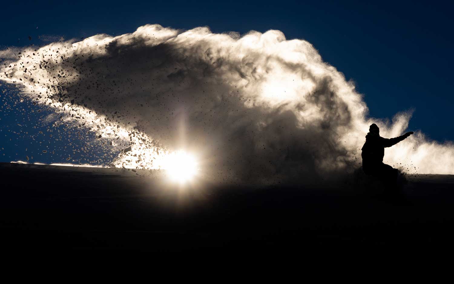 Silhouette of a person with a bright sun and dramatic cloud formation.
