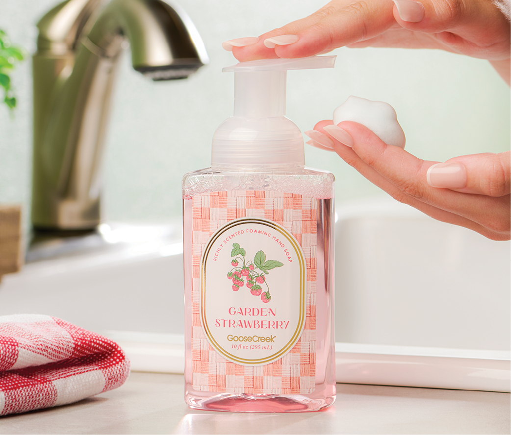 A person dispensing liquid from a decorative hand soap bottle in a bathroom.