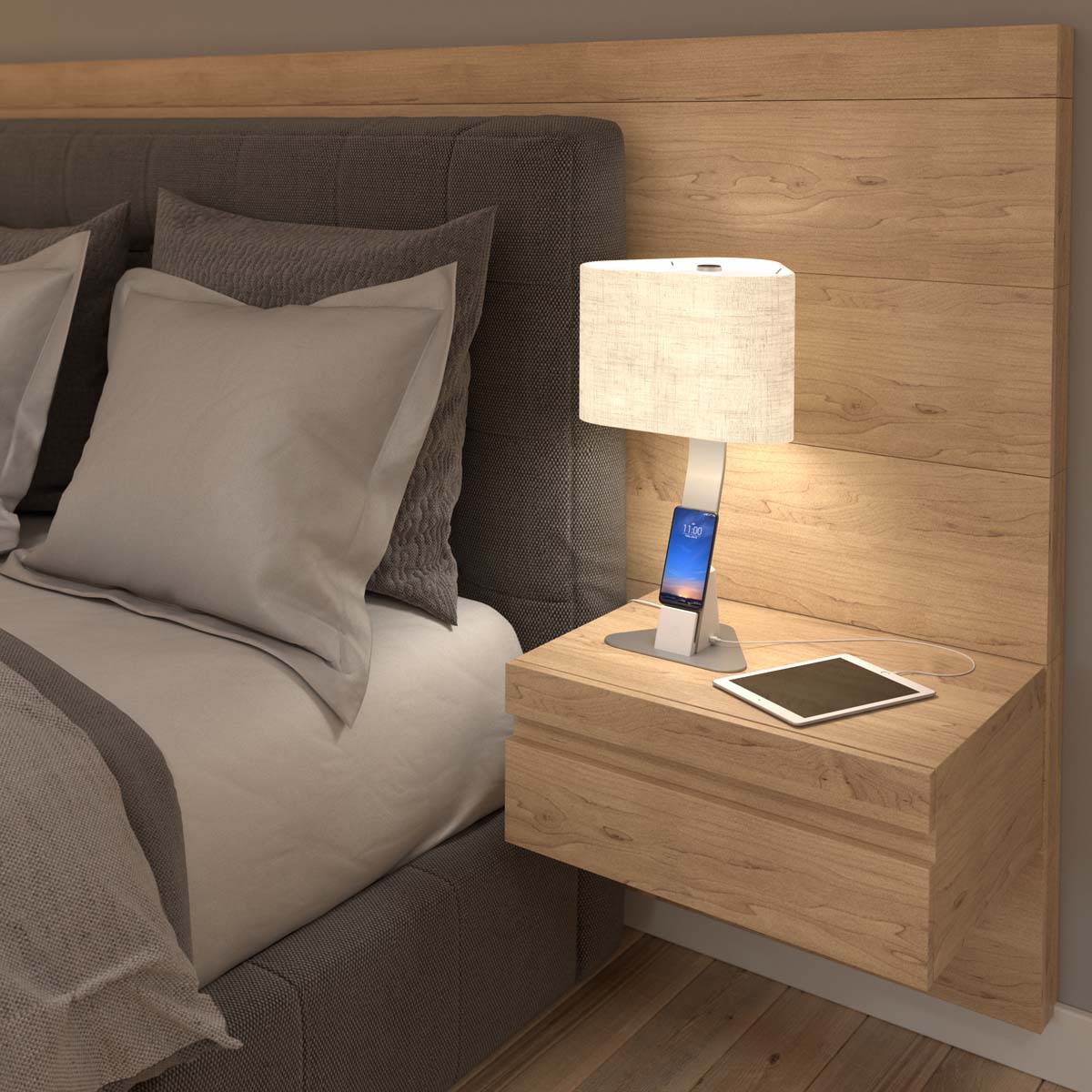 A LUX lamp charges a smartphone and a tablet on a bedside table.