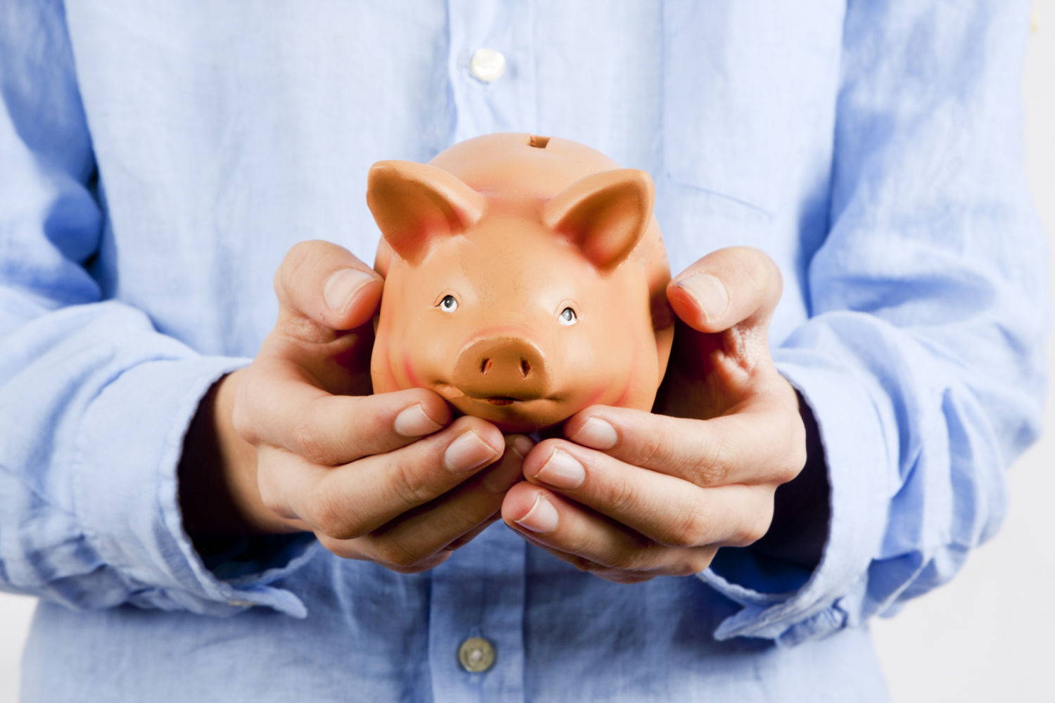A person in a blue shirt holding out their piggy bank in their hands
