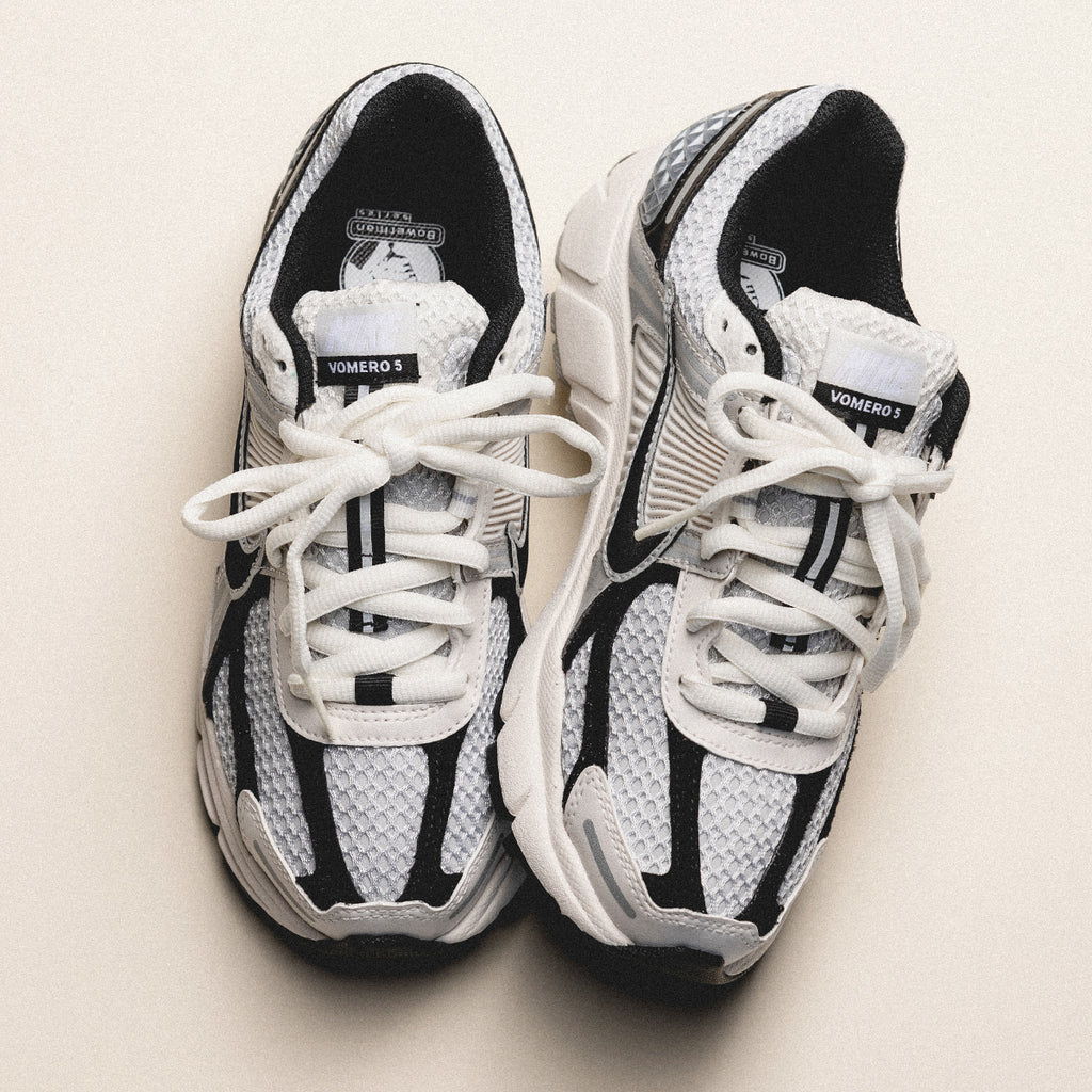 A pair of black and white athletic shoes with laces.