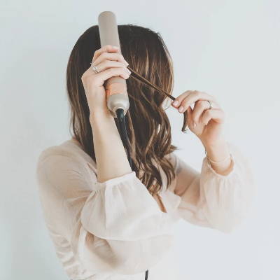 bronde model using all in one styling iron right side of hair in blush shirt