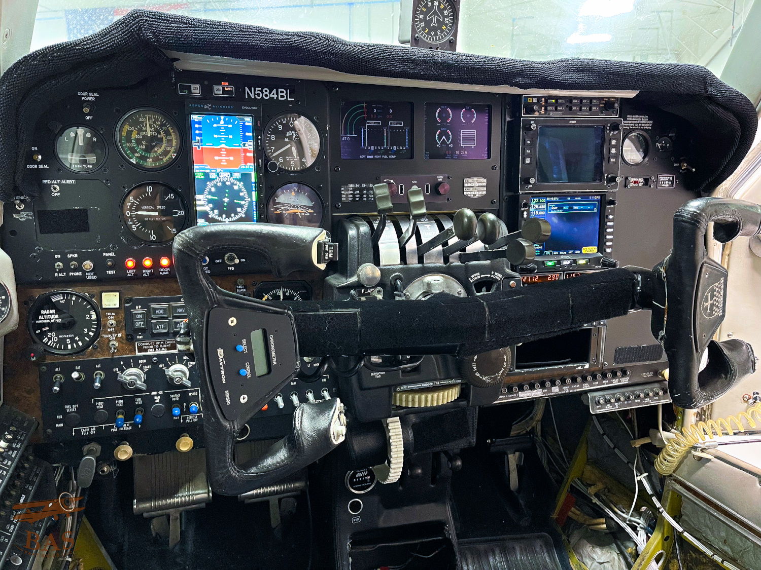 Aircraft cockpit with various gauges, controls, and screens.