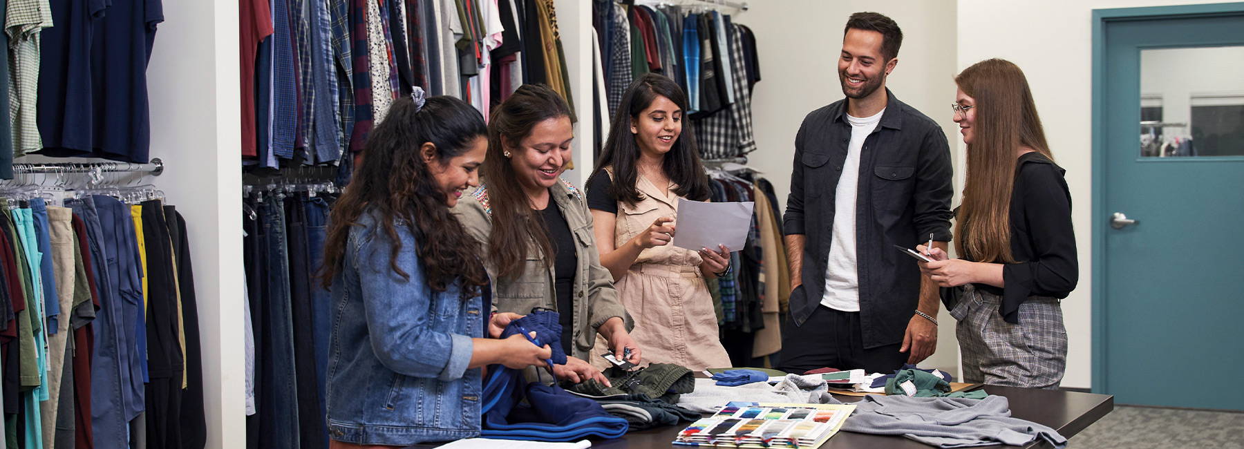 Team members standing around a table looking at clothing swatches