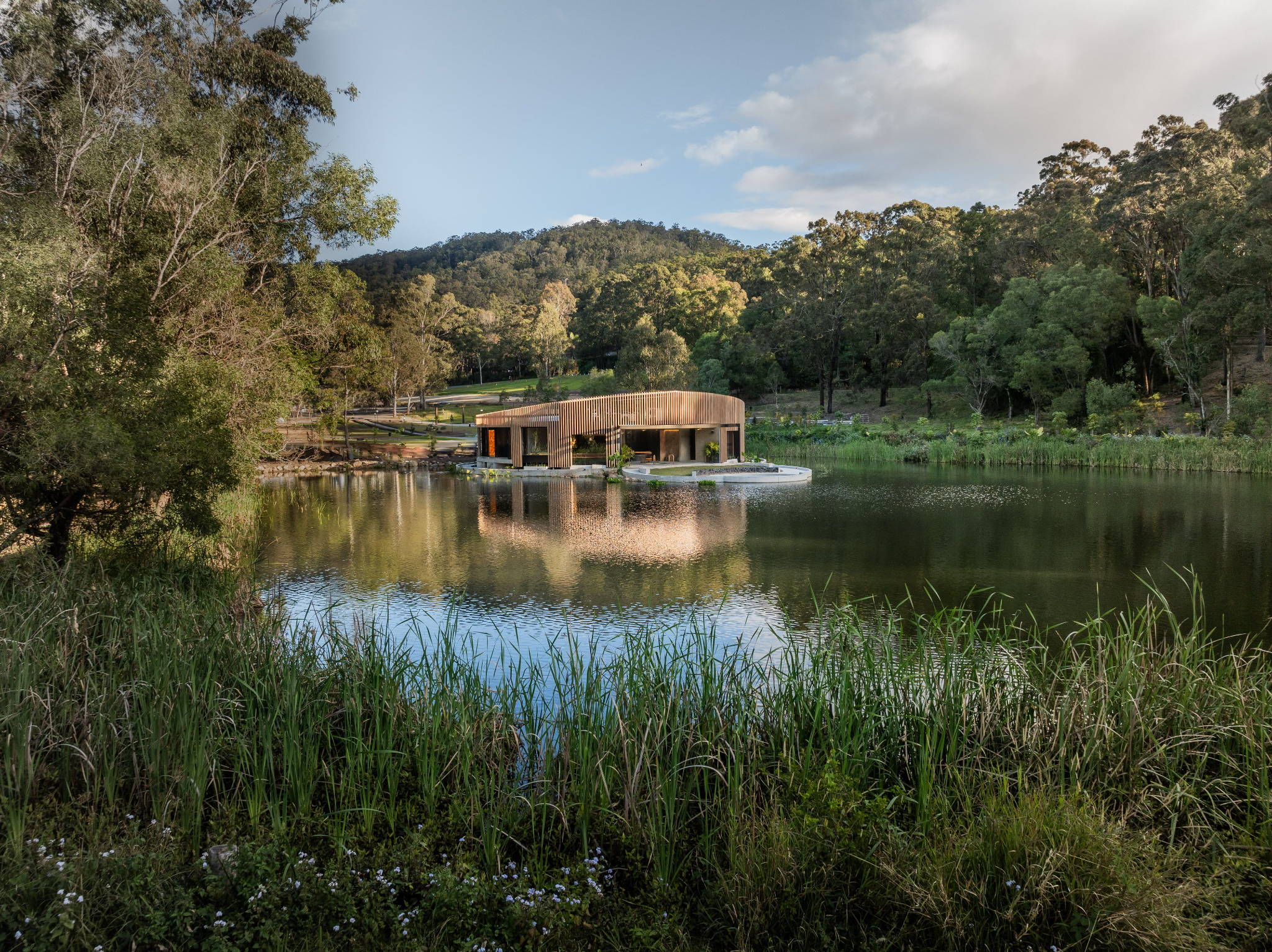 Scenic view of a building by a calm lake surrounded by greenery.