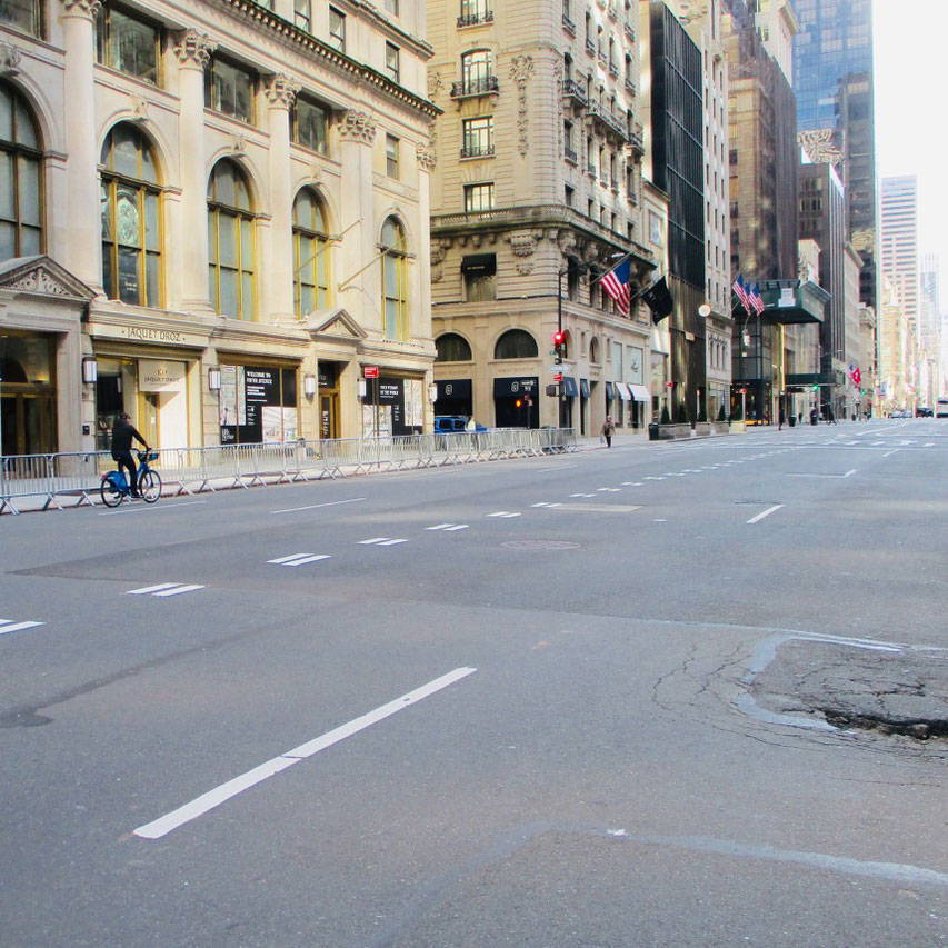 A person riding a bike towards a single pedestrian on an empty New Your City street