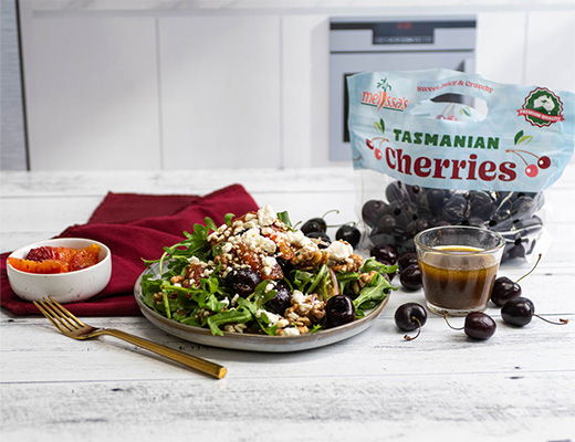 A salad with cherries, dressing, and a bag of Tasmanian cherries.