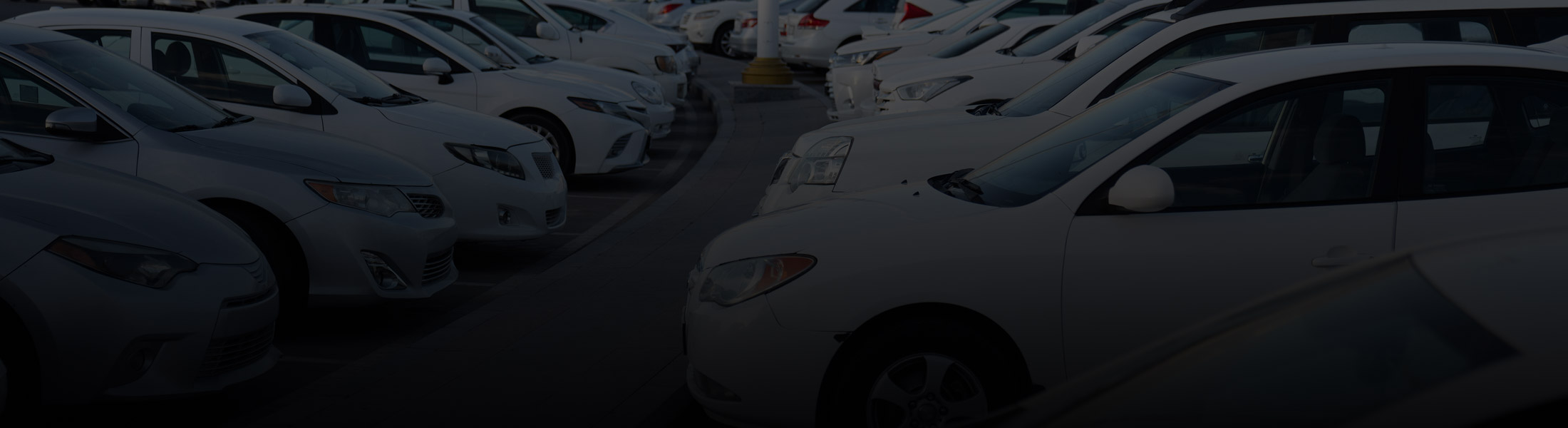 Car dealership lot with rows of parked vehicles, representing security and monitoring solutions for automotive businesses