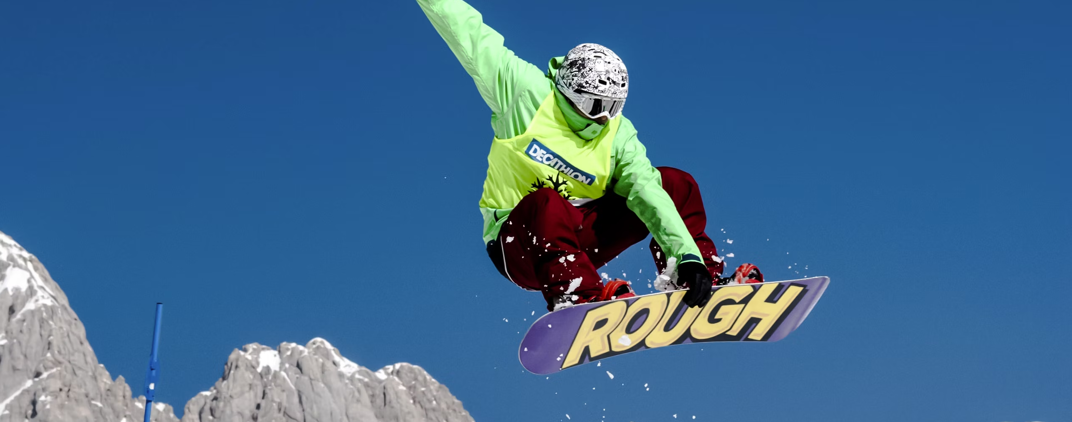 Person snowboarding in mid-air against a clear blue sky.
