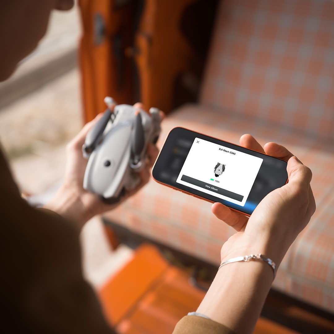 Person holding a DJI Lito series drone and a smartphone displaying a connection screen.