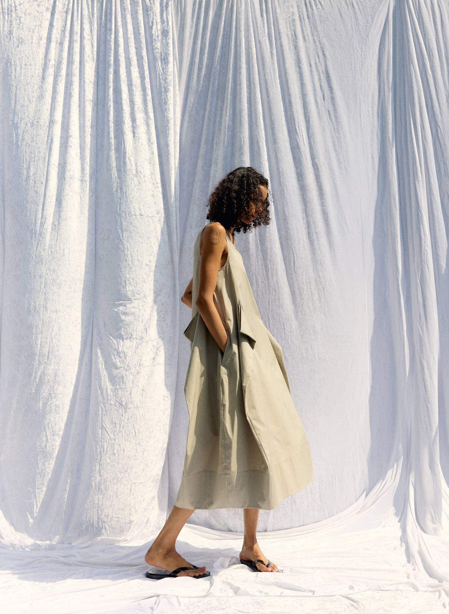A person in a light dress walking against a white backdrop.