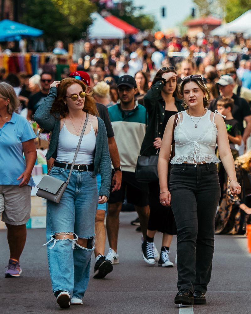 Crowd of people walking at a street fair or market.