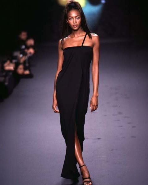 A model walking on a runway wearing a black dress.