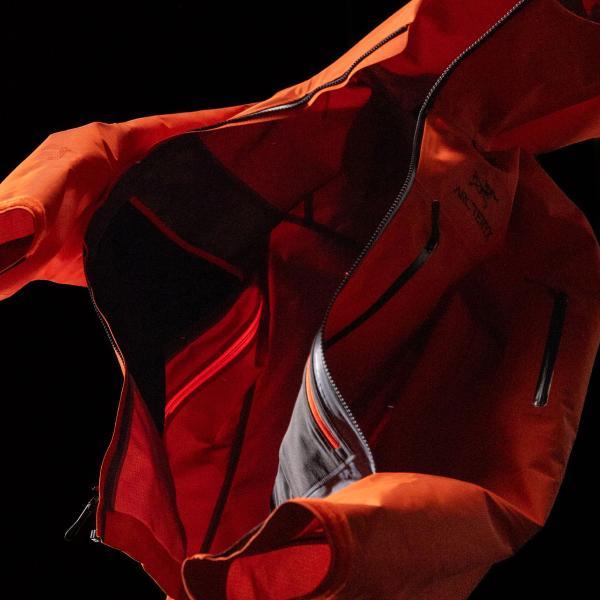 An open orange jacket revealing its interior pockets and lining.