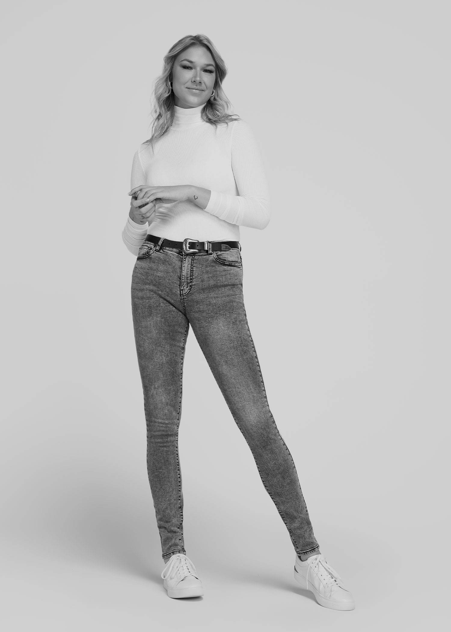 Tall model wearing a white turtleneck and grey jeans in black and white