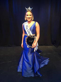 A person wearing a blue dress holding a trophy.
