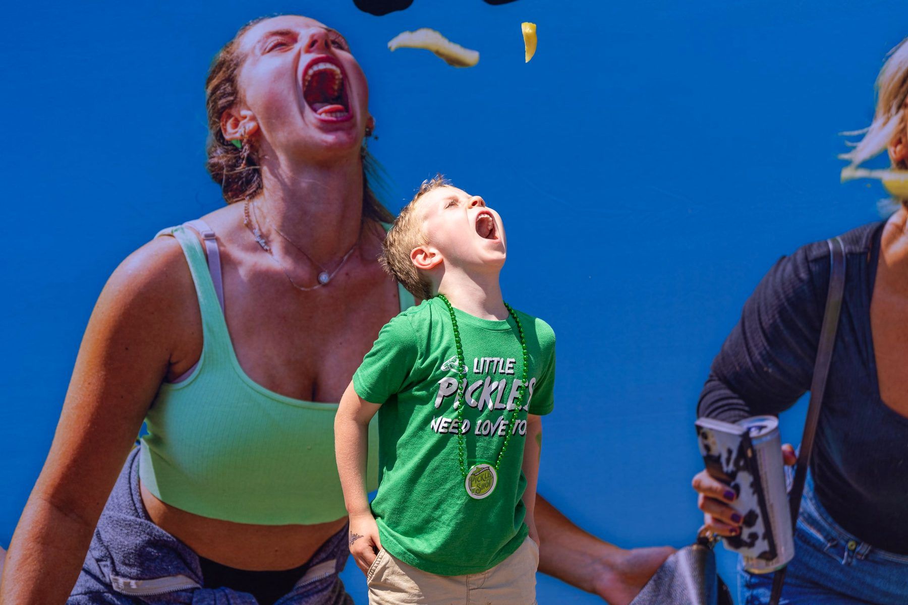A young kid catching tossed pickles in front of the activation wall during the Pickle Pitching activation at The Big Dill Philadelphia 2024.