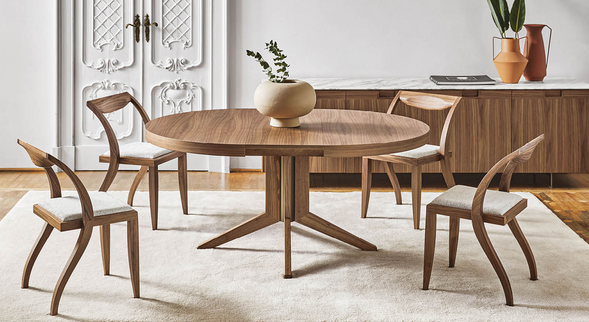 Wooden Bryant Extendable Dining by Porada table with four chairs and a decorative vase.