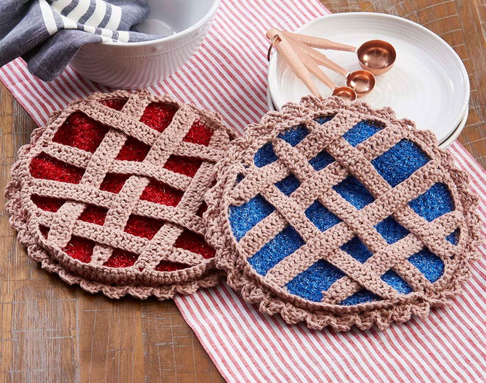 Two round, crocheted pot holders that look like lattice pies in red and blue on a table.