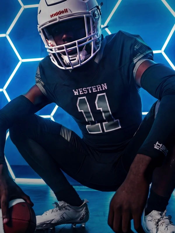 Football player in uniform, posing with a football against a geometric background.