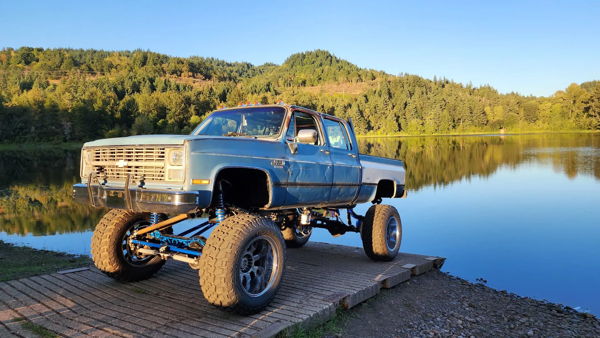 Front three-quarter view of Joseph's lifted blue 1981 Chevy K30 parked by the water, install photo 1