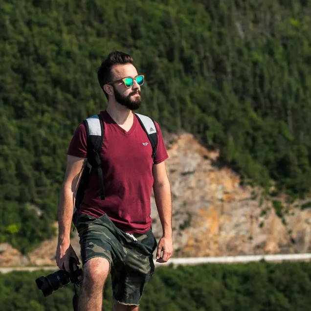 Man hiking wearing Racer, Square Polarized Sunglasses with a red shirt holding a camera