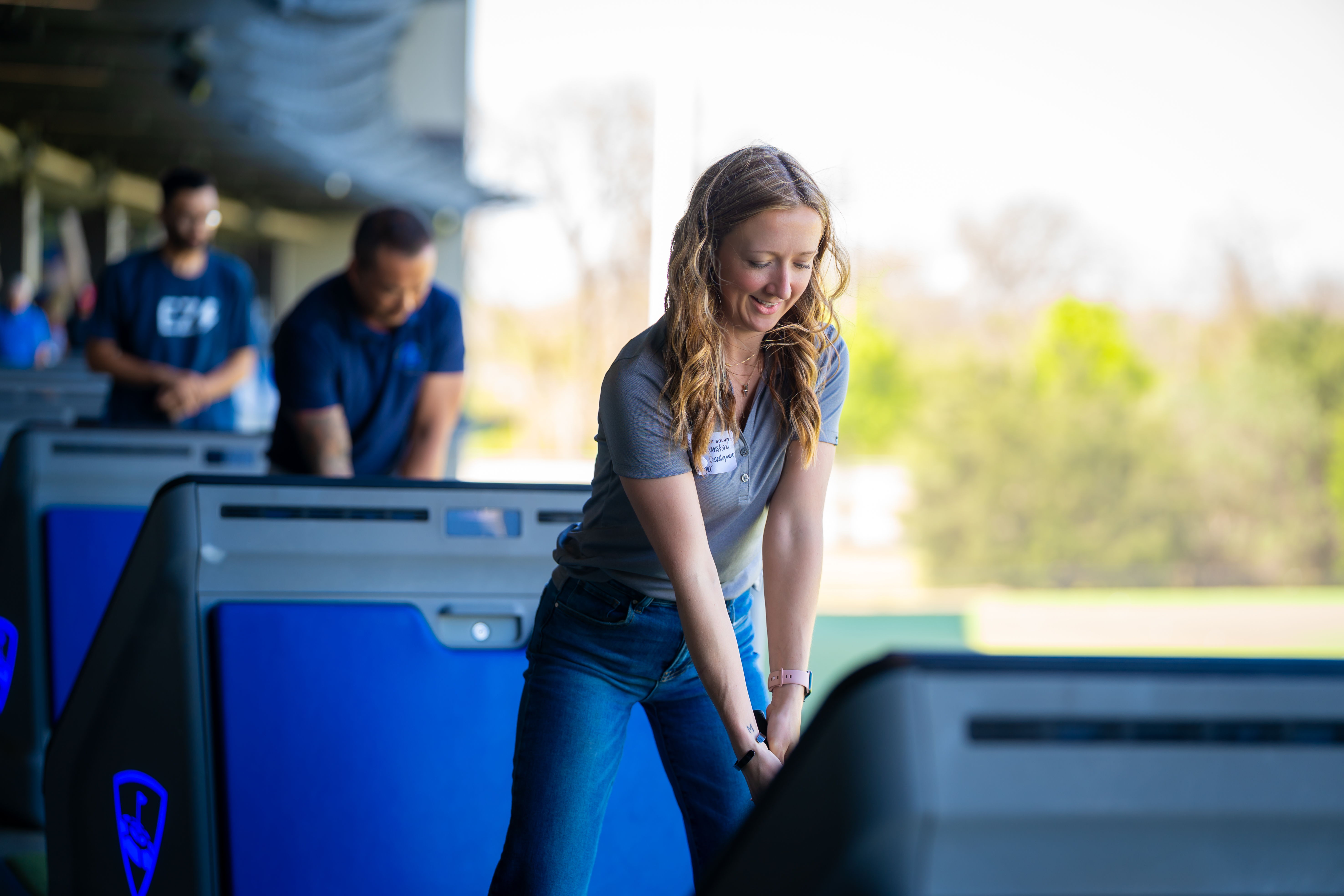 A woman golfing at a driving range, smiling and focused.